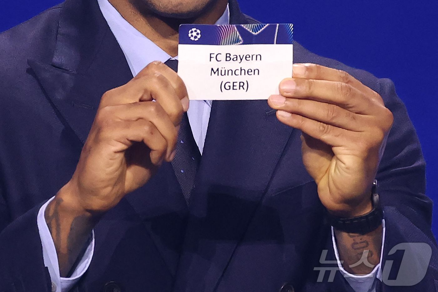 본문 이미지 - 티에리 앙리가 28일(한국시간) 모나코에서 열린 2026-27 UEFA 챔피언스리그 리그 페이즈 추첨식에서 바이에른 뮌헨이 적힌 용지를 들고 있다. ⓒ AFP=뉴스1