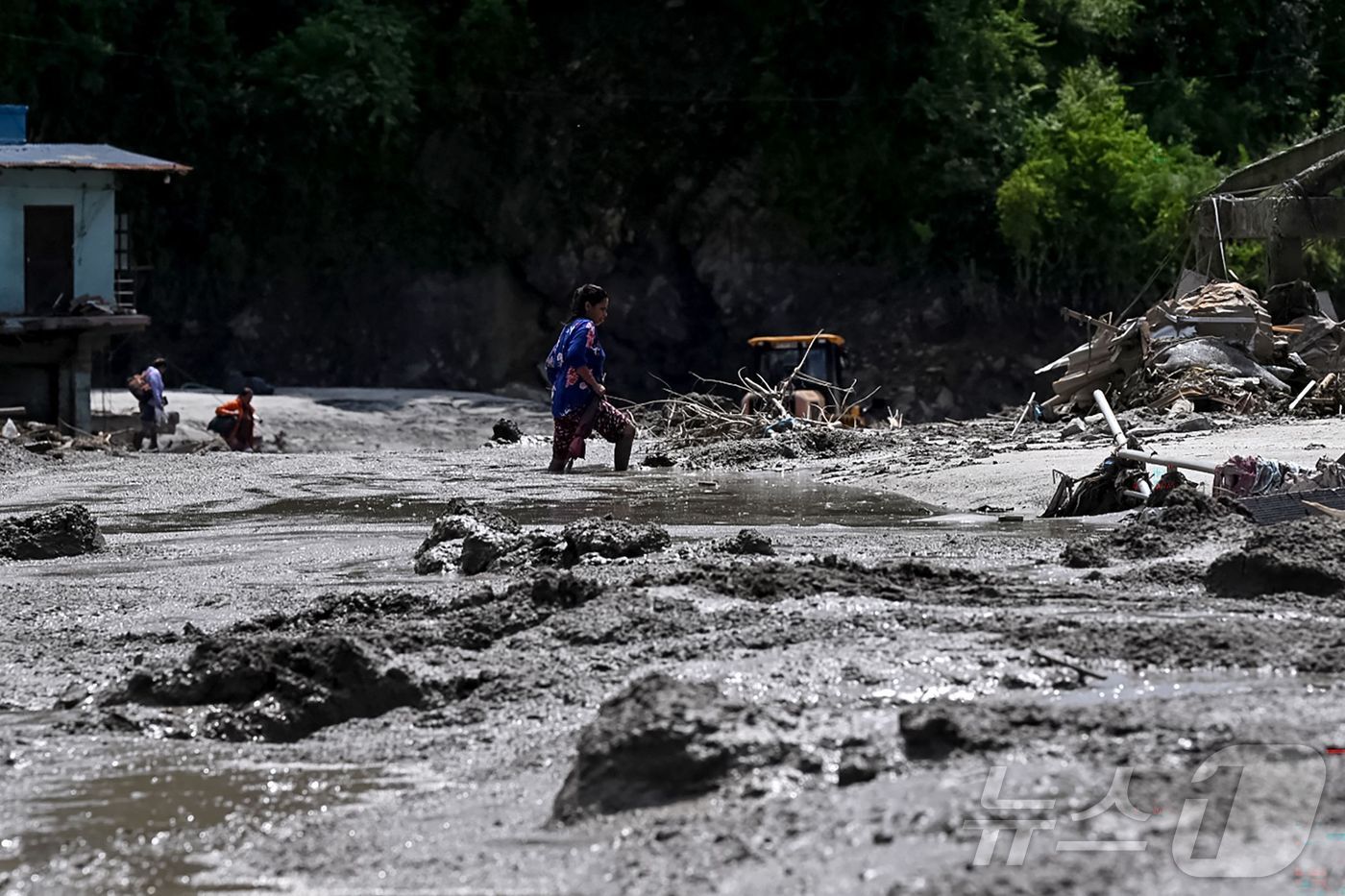 (누와코트 AFP=뉴스1) 윤지오 수습기자 = 27일(현지시간) 네팔 누와코트 데비가트에서 한 여성이 홍수로 인해 진흙과 잔해에 잠긴 도로를 헤치며 걸어가고 있다. 2026.08. …