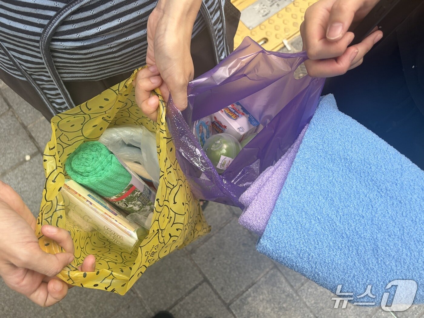 본문 이미지 - 27일 서울 중구 남대문시장에서 청년들이 저렴한 가격에 구매한 사우나 용품 등을 들고 있다. 2026.8.27 ⓒ 뉴스1 안소연 수습기자