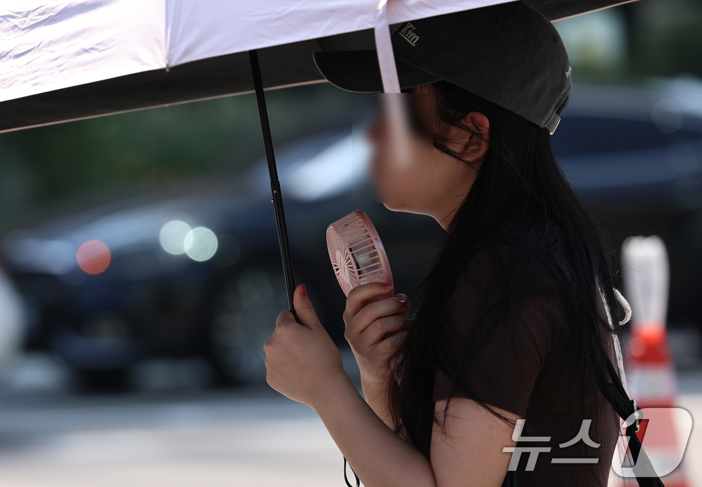 (서울=뉴스1) 구윤성 기자 = 강원 일부 지역을 제외한 전국에 폭염특보가 내려진 3일 오전 서울 광화문 네거리에서 한 시민이 양산과 휴대용 선풍기로 더위를 식히고 있다. 2026 …