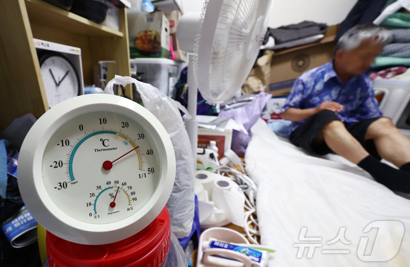 본문 이미지 - 서울 최고 기온이 37도까지 오르는 등 기록적인 폭염이 이어지고 있는 3일 서울의 한 쪽방촌에서 어르신이 선풍기 한 대에 의지해 더위를 식히고 있다. 사진 속 온도계는 35도 가까이를 가리키고 있다. 2026.8.3 ⓒ 뉴스1 김민지 기자