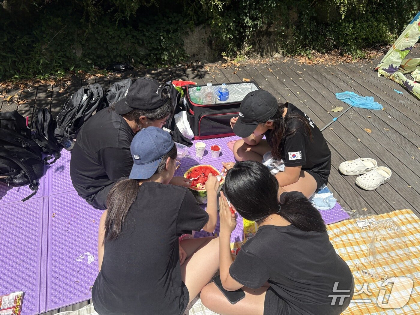 본문 이미지 - 인천에서 온 중학교 2학년 김 모 양 등 친구 4명은 땡볕 아래 돗자리를 펴고 연신 땀을 닦으며 수박 한 통을 나눠 먹는 모습.  2026.8.8/뉴스1 ⓒ News1 소봄이 기자