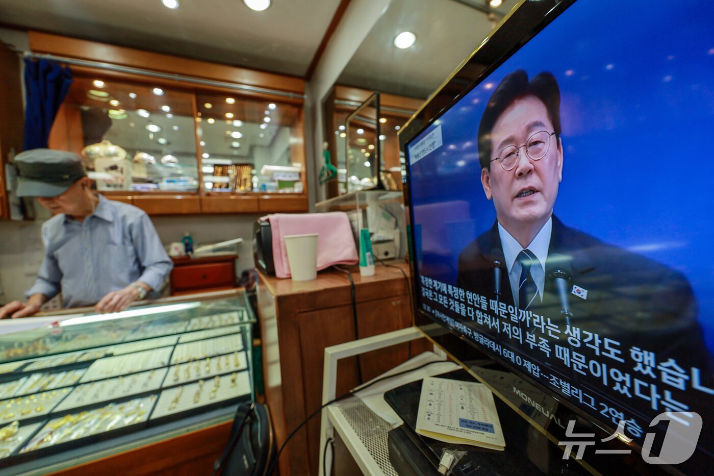 본문 이미지 - 18일 서울 한 전통시장에서 상인이 이재명 대통령의 기자회견 뉴스를 지켜보고 있다. 2026.9.18 ⓒ 뉴스1 이호윤 기자