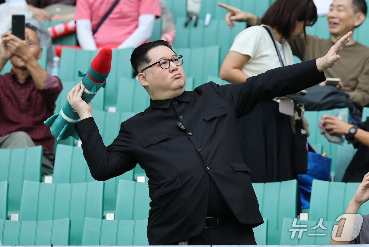 본문 이미지 - 21일 일본 시즈오카 스타디움 에코파에서 열린 2026 아이치·나고야 아시안게임 조별예선 F조 대한민국과 북한의 경기를 찾은 중국계 정치활동가 '하워드X'가 북한 김정은 국무위원장이 로켓을 든 모습을 표현하고 있다. 2026.9.21 ⓒ 뉴스1 안은나 기자
