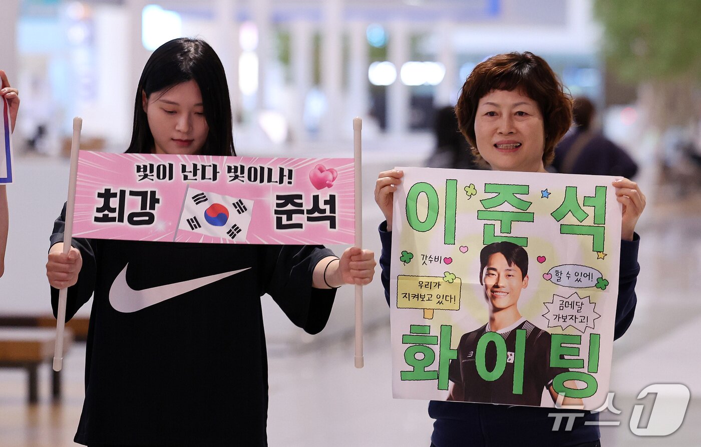 본문 이미지 - 2026 아이치·나고야 아시안게임 테크볼 남자 단식에서 금메달을 차지한 이준석의 어머니와 누나가 21일 인천국제공항 제2여객터미널에서 이준석의 인터뷰를 기다리며 응원 현수막을 들고 있다. 2026.9.21 ⓒ 뉴스1 박지혜 기자