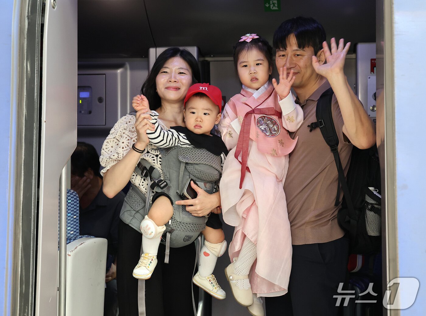 본문 이미지 - 추석 연휴를 하루 앞둔 23일 서울역에서 귀성길에 오른 한 가족이 열차에 탑승해 인사하고 있다. 2026.9.23 ⓒ 뉴스1 김성진 기자