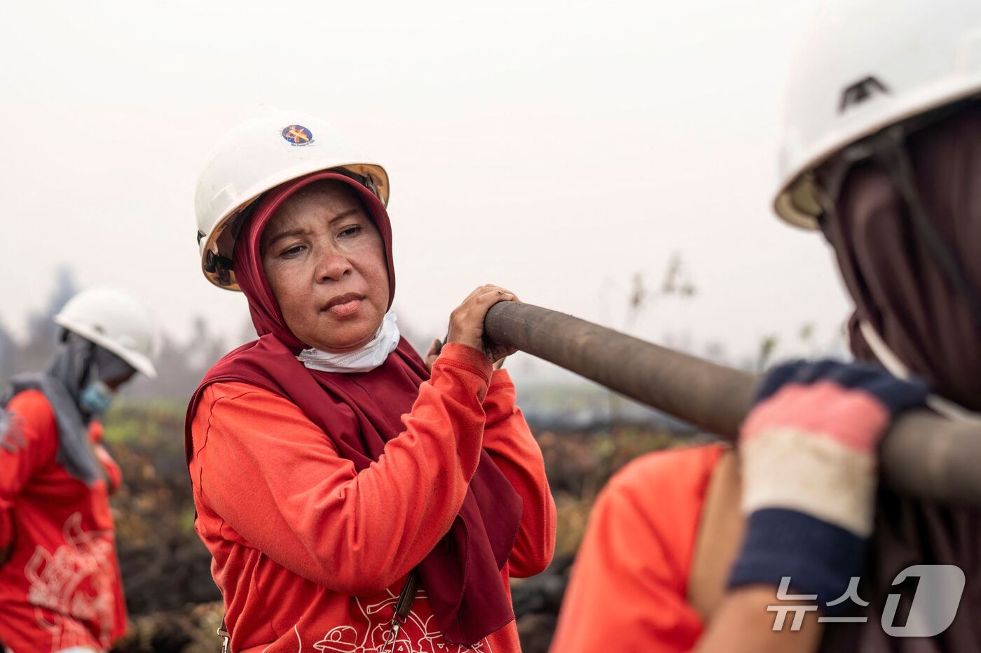 (크타팡 AFP=뉴스1) 김범수 기자 = 26일(현지시간) 여성 자원봉사 소방대 '더 파워 오브 마마'(TPoM) 대원들이 인도네시아 서칼리만탄 크타팡의 한 마을에서 연기가 피어오 …