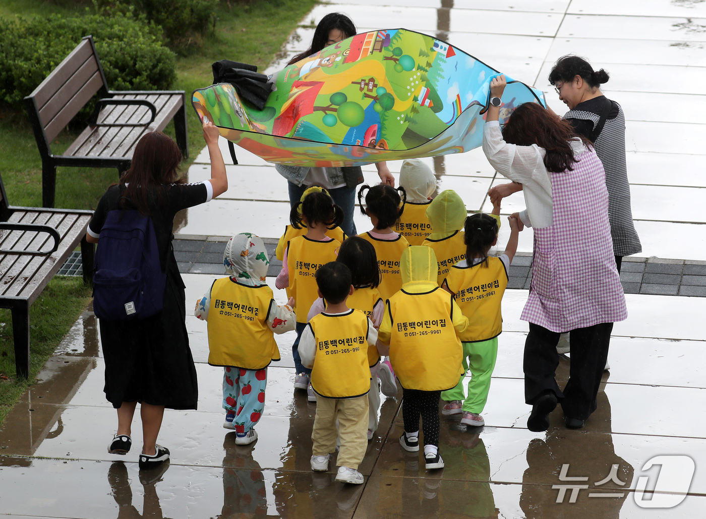(부산=뉴스1) 윤일지 기자 = 29일 부산 동구 북항 친수공원에서 보육교사들이 돗자리를 펼친 채 원생들이 비를 맞지 않게 막아 주고 있다. 2026.9.29/뉴스1