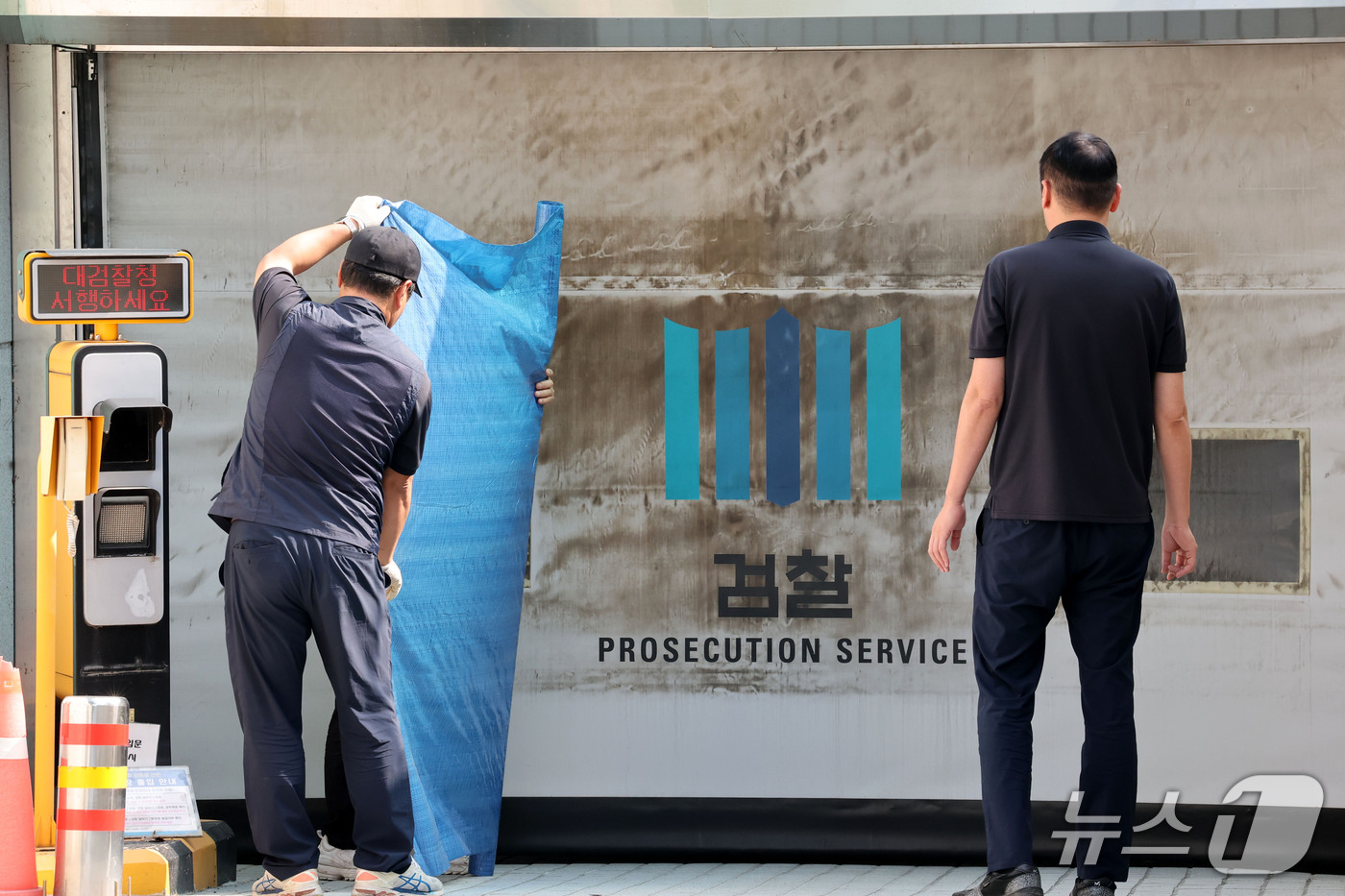 (서울=뉴스1) 이광호 기자 = 공소청·중대범죄수사청 출범을 이틀 앞둔 30일 서울 서초구 대검찰청에서 관계자들이 주차장 출입문에 새겨진 검찰 표식을 가리기 위한 준비작업을 하고 …