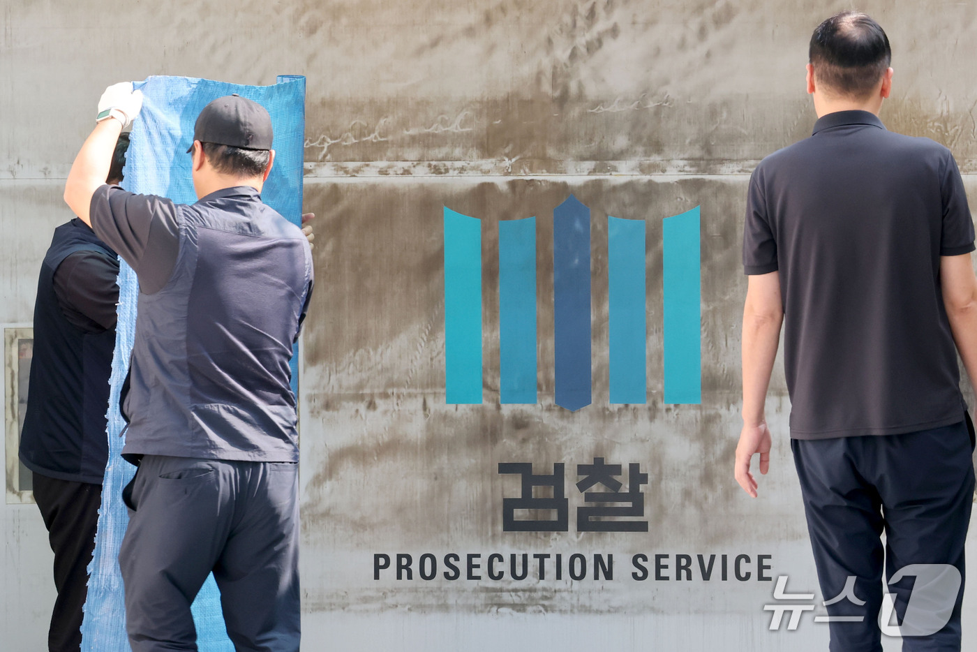 (서울=뉴스1) 이광호 기자 = 공소청·중대범죄수사청 출범을 이틀 앞둔 30일 서울 서초구 대검찰청에서 관계자들이 주차장 출입문에 새겨진 검찰 표식을 가리기 위한 준비작업을 하고 …