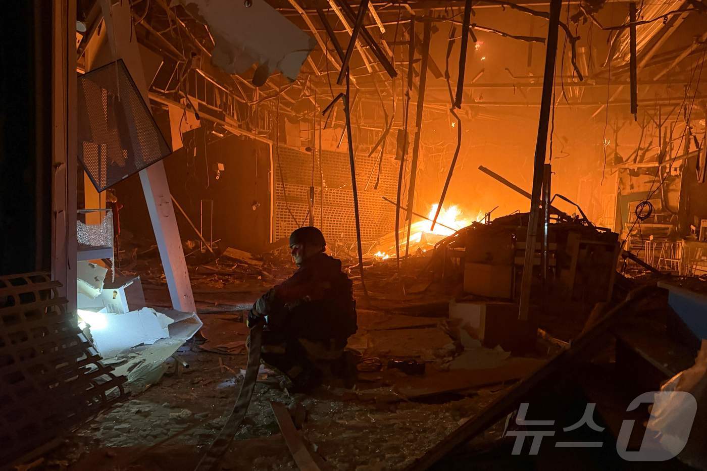 (자포리자 AFP=뉴스1) 김범수 수습기자 = 7일(현지시간) 우크라이나 자포리자에서 러시아군의 공습으로 한 쇼핑몰에서 불이 난 가운데 우크라이나 구조대원이 진화 작업을 벌이고 있 …